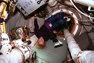 STS-81 mission specialist Marsha Ivins is photographed in the Kristall module (just at the entrance to the Docking module) holding the electronic still camera.